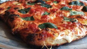 Close up view of a sourdough pizza with tomatoes, cheese and spinach from Ops in NYC, New York, USA